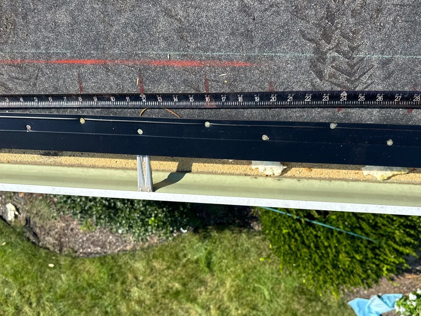 Black drip edge nailed along the eave with a tape measure above it