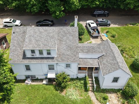 After: aerial view of the white two-story house and its rear wing with a new gray shingle roof