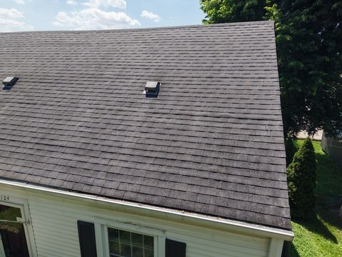 Before: a worn, dark shingle slope with a roof vent, seen from the yard