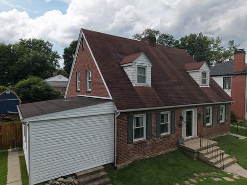 Before: brick Cape Cod with two front dormers and its worn shingle roof