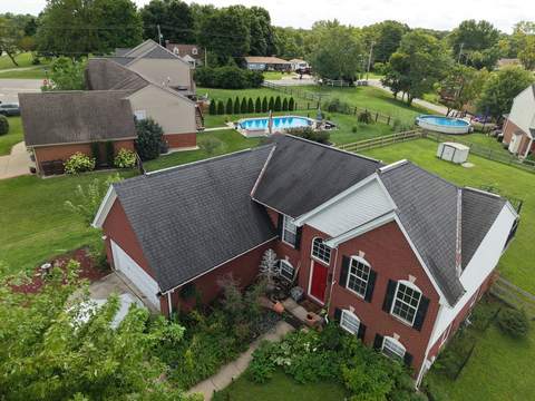 Before: two-story brick and vinyl home from above with its old dark roof