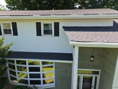 After: the front of the same home with its new gray roof over the entry