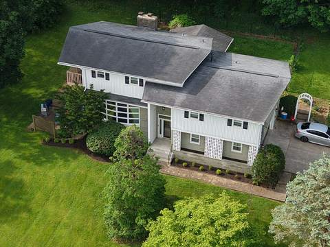 Before: two-story home seen from above with its old gray roof