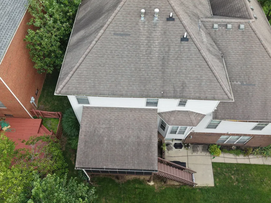 Aerial view of the back of the same house showing storm-damaged, worn shingles