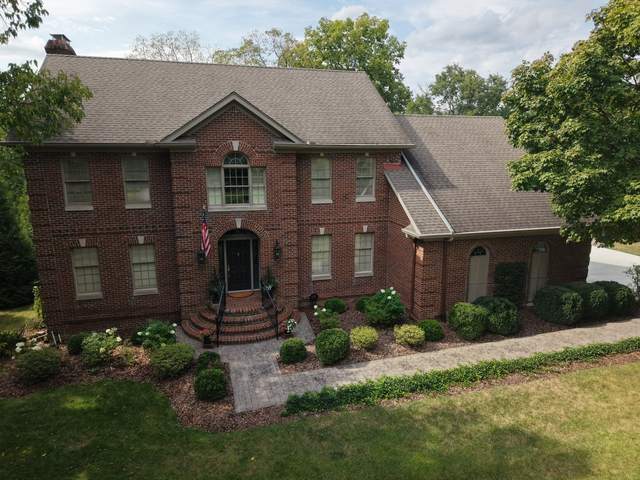 Before: two-story brick home with a weathered brown shingle roof, seen from above the front
