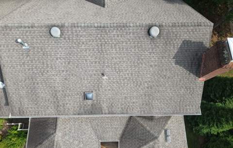 Top-down drone view of the old weathered roof at inspection, with its roof vents and a skylight