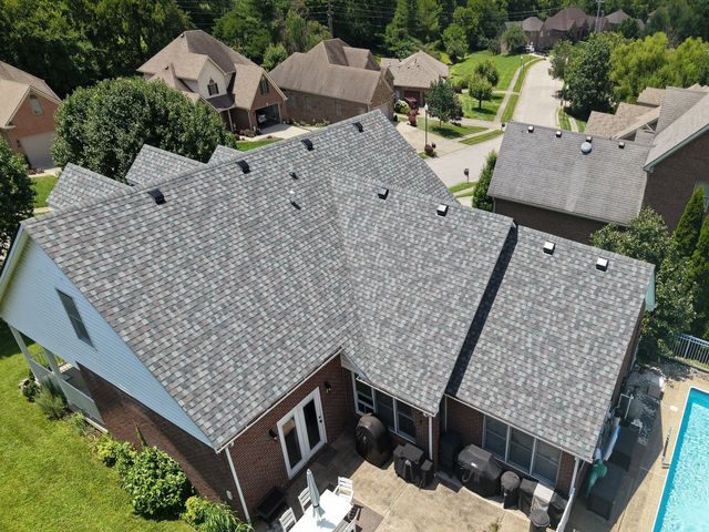 After: the same home from the same rear drone angle with a new light-gray shingle roof